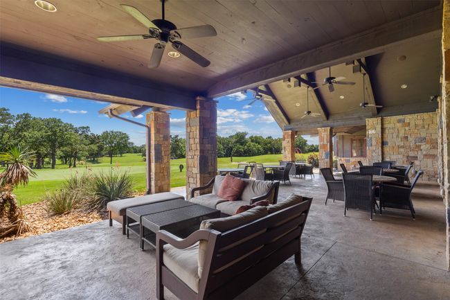 View of patio / terrace with outdoor dining space, a ceiling fan, outdoor lounge area, golf course view, and view of scattered trees | Image 11