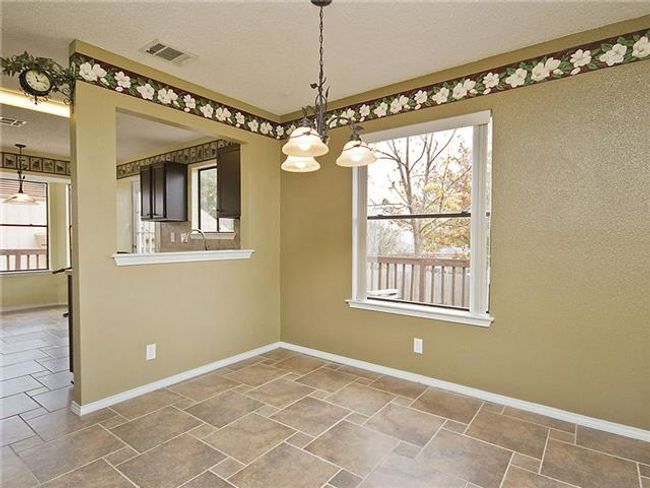 Unfurnished dining area with a wealth of natural light, stone tile flooring, and a notable chandelier | Image 5
