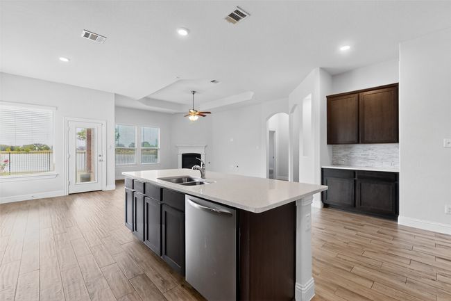 Kitchen featuring stainless steel dishwasher, arched walkways, a ceiling fan, light wood-style flooring, and recessed lighting | Image 10