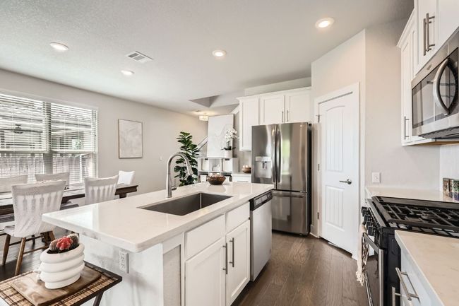 Kitchen with appliances with stainless steel finishes, a center island with sink, dark wood-type flooring, white cabinetry, and recessed lighting | Image 9