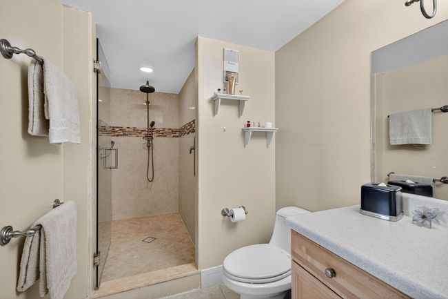 Tastefully Renovated Primary Bath with Glass Tile Inset, Frameless Shower Door and Elegant Oak Vanity with Storage closet ensuite | Image 29