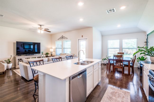 Kitchen featuring dishwasher, a breakfast bar, a center island with sink, light countertops, and white cabinetry | Image 9