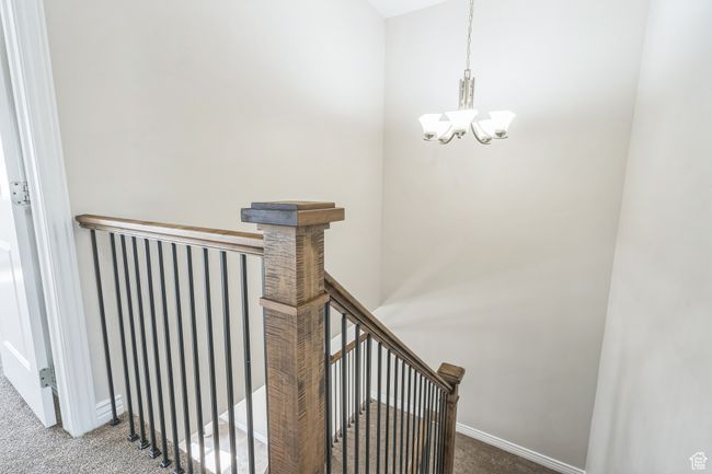 Stairway with carpet flooring and a chandelier | Image 7