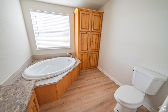Full bathroom featuring wood finished floors, a garden tub, and toilet | Image 32