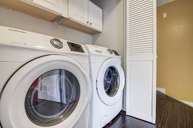Laundry room with cabinet space, washing machine and clothes dryer, and dark wood-type flooring | Image 11