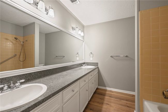 Bathroom with double vanity, wood finished floors, toilet, washtub / shower combination, and a textured ceiling | Image 18