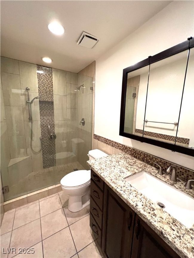 Full bathroom with a stall shower, tile patterned floors, toilet, vanity, and visible vents | Image 25