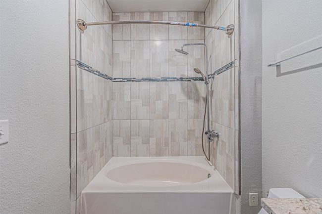 Full bath featuring a textured wall and shower / bathtub combination | Image 10