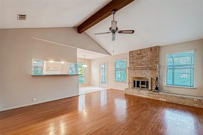 Charming living space featuring an elegant brick fireplace and rustic wood-beamed ceilings. | Image 2