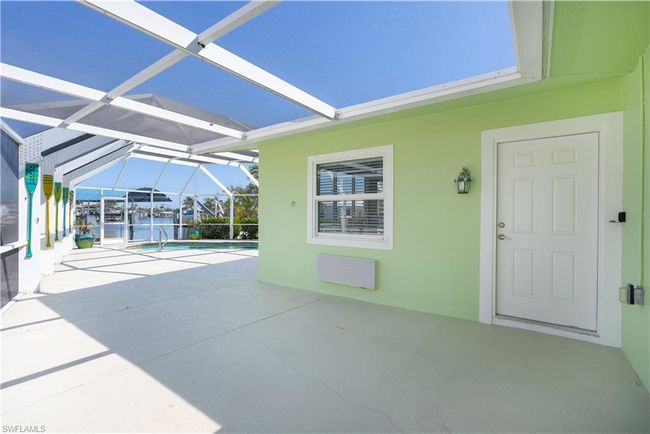 View of patio with an outdoor pool, a water view, and a lanai. | Image 15