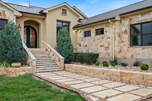 Property entrance featuring a stone stair entrance and paver walkway. | Image 5