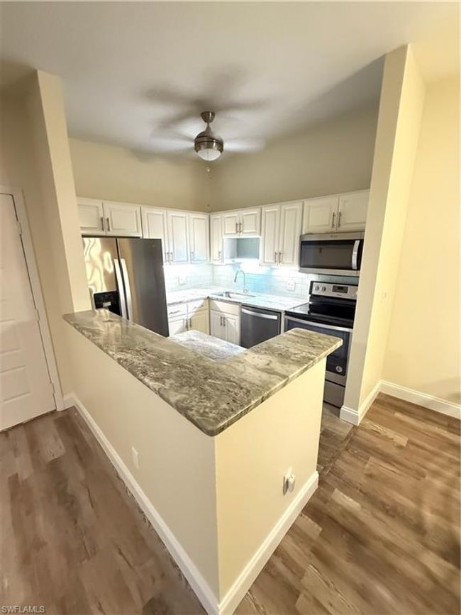Kitchen featuring refrigerator, a sink, dishwasher, light stone countertops, and stove | Image 4