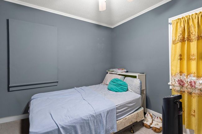 Bedroom two located at the front of the home adjacent to the living room is fitted with carpeting, ceiling fan and views of the side of the home. | Image 10