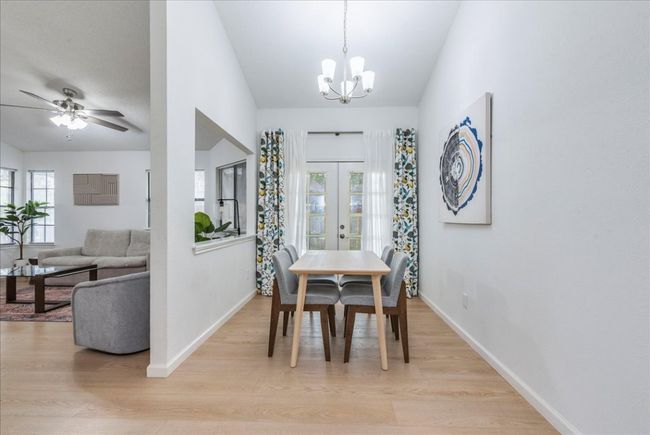 Dining space with baseboards, light wood-type flooring, french doors, and ceiling fan with notable chandelier | Image 7