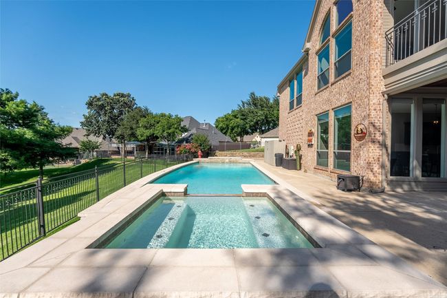 View of swimming pool with a fenced backyard, a patio area, and a pool with connected hot tub | Image 11