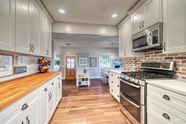 Kitchen with appliances with stainless steel finishes, decorative backsplash, light wood-style floors, white cabinetry, and recessed lighting | Image 10