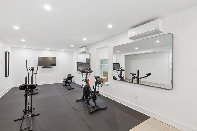 Workout area with a wall mounted AC, recessed lighting, and baseboards | Image 23