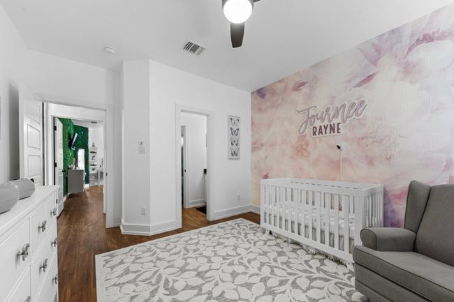 Bedroom with visible vents, baseboards, dark wood-style flooring, ceiling fan, and a crib | Image 27