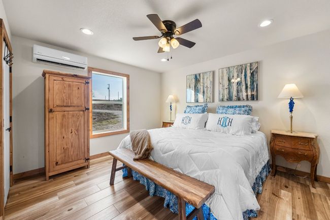 Bedroom with light wood-type flooring, recessed lighting, a wall mounted air conditioner, and baseboards | Image 20