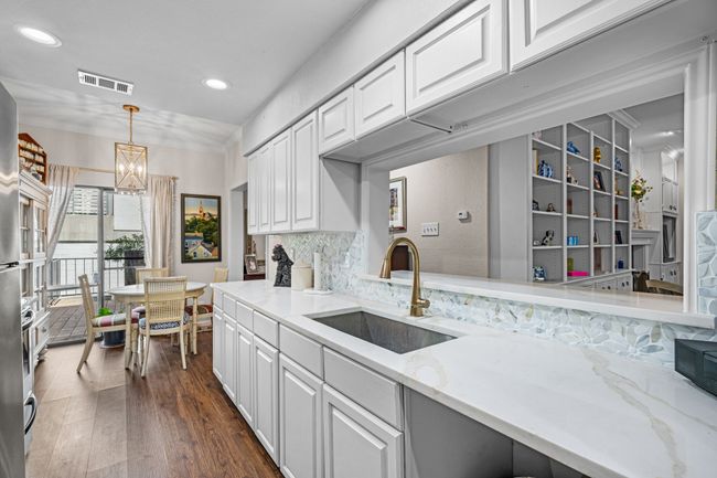 Kitchen featuring white cabinets, dark wood-style floors, a chandelier, light stone countertops, and recessed lighting | Image 7