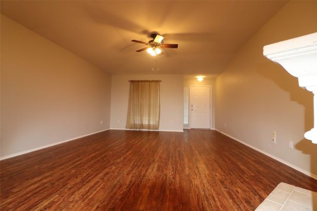 Unfurnished living room featuring dark wood-type flooring, a ceiling fan, and vaulted ceiling | Image 8