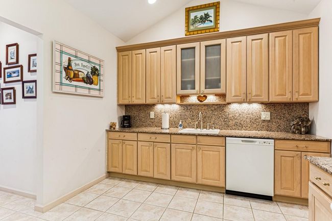 Kitchen featuring lofted ceiling, backsplash, a sink, light tile patterned flooring, and dishwasher | Image 28