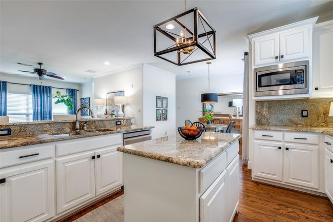 Kitchen featuring stainless steel appliances, tasteful backsplash, a center island, ornamental molding, and white cabinets | Image 12