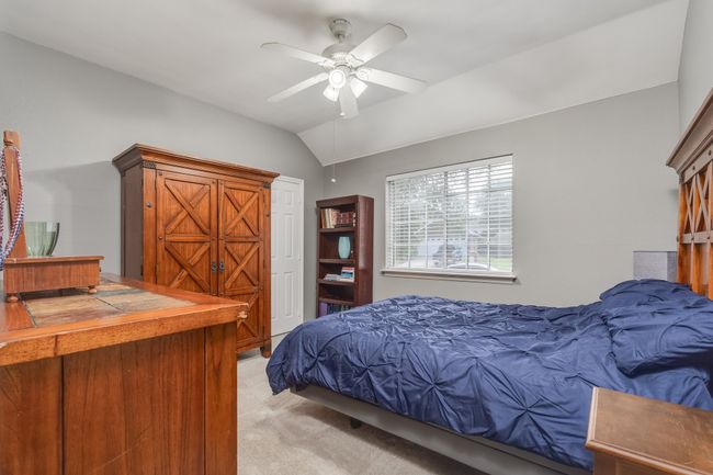 Bedroom featuring light colored carpet, lofted ceiling, and ceiling fan | Image 11