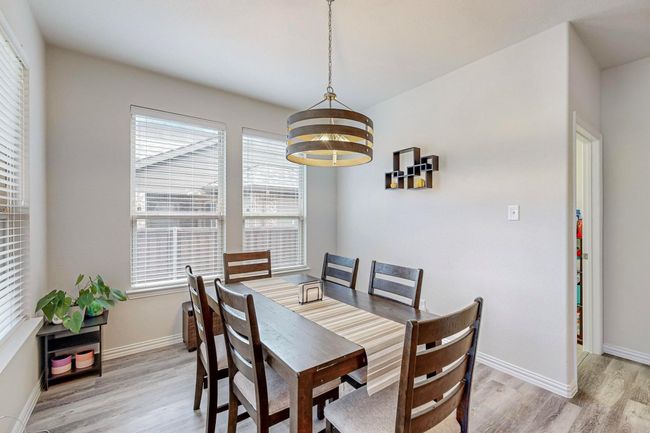 Dining room featuring light wood-type flooring, a chandelier, and baseboards | Image 4