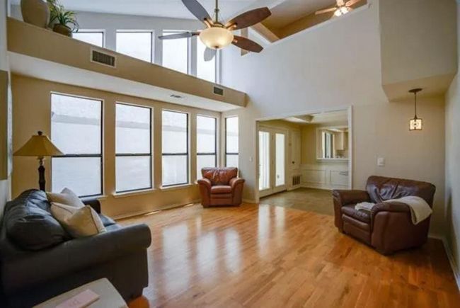 Living area featuring a ceiling fan, wood finished floors, and a towering ceiling | Image 21