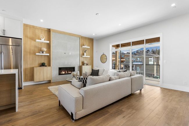 Living area with wood finished floors, a fireplace, baseboards, recessed lighting, and built in shelves | Image 10