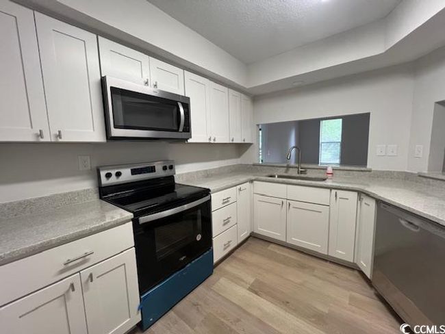 Kitchen featuring light countertops, white cabinetry, a sink, light wood-style flooring, and stainless steel appliances | Image 26