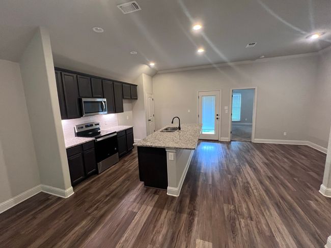 Kitchen featuring stainless steel appliances, a center island with sink, baseboards, backsplash, and a sink | Image 26
