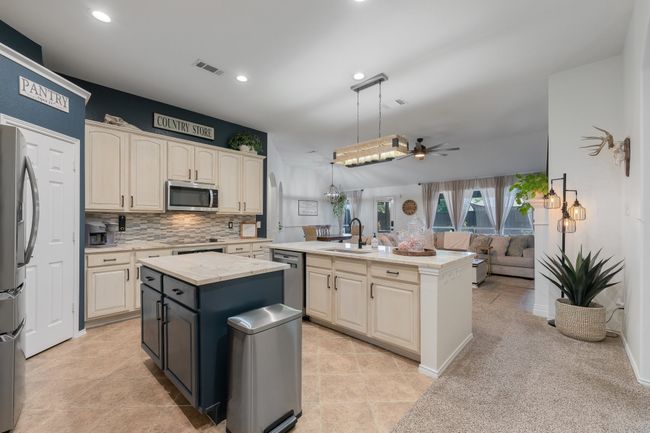 Kitchen with a kitchen island with sink, appliances with stainless steel finishes, a sink, cream cabinetry, and a ceiling fan | Image 13