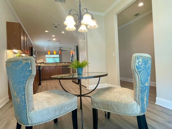 Dining area featuring light wood finished floors, crown molding, a chandelier, and recessed lighting | Image 5