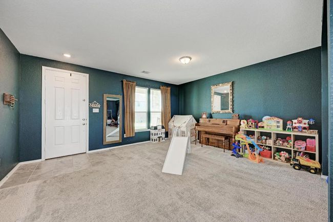 Rec room with a textured wall and carpet flooring | Image 8