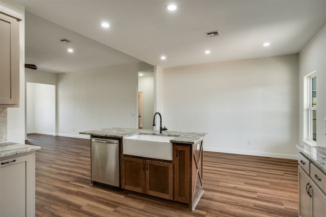 Kitchen featuring dark wood-style floors, a kitchen island with sink, stainless steel dishwasher, and a sink | Image 12