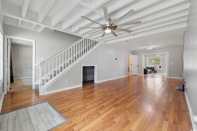 Unfurnished living room featuring stairway, ceiling fan, beam ceiling, light wood-style flooring, and baseboards | Image 24