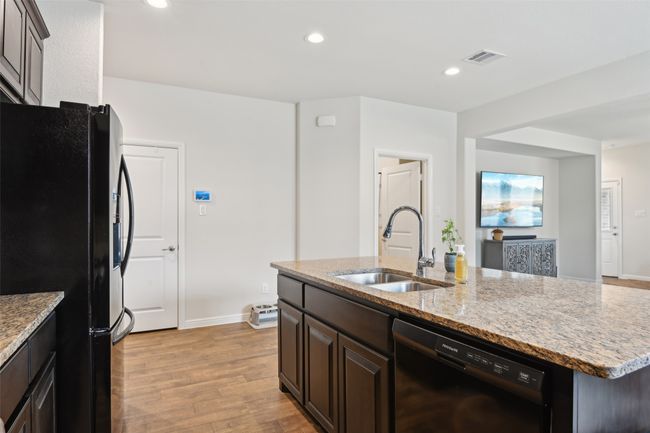 Kitchen featuring black appliances, a sink, light wood-style floors, a kitchen island with sink, and light stone countertops | Image 13
