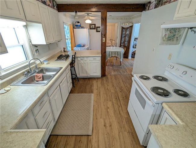 Kitchen featuring white cabinets, a sink, light wood-style floors, light countertops, and electric stove | Image 15