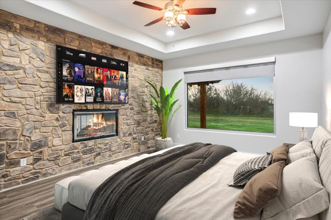 Bedroom featuring hardwood / wood-style floors, a raised ceiling, ceiling fan, and a stone fireplace | Image 6