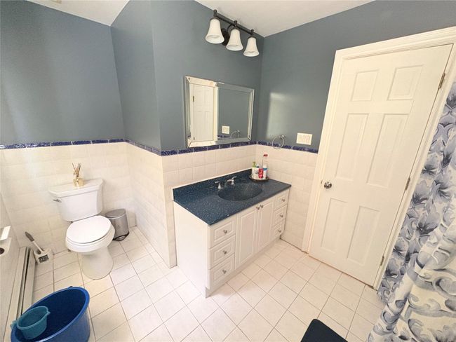 Full bath with tile walls, tile patterned floors, a wainscoted wall, toilet, and vanity | Image 15