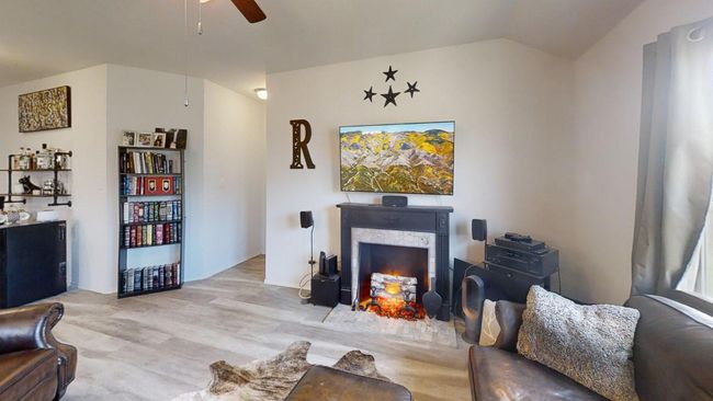 Living room with ceiling fan, lofted ceiling, a lit fireplace, and light wood-style floors | Image 23