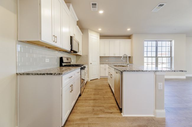 Kitchen with appliances with stainless steel finishes, a kitchen island with sink, white cabinets, tasteful backsplash, and recessed lighting | Image 11