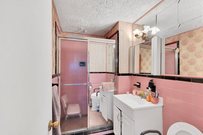 Bathroom with vanity, a shower stall, wallpapered walls, a wainscoted wall, and tile walls | Image 7