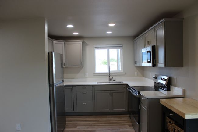 Kitchen with appliances with stainless steel finishes, recessed lighting, wood finished floors, light countertops, and gray cabinets | Image 7