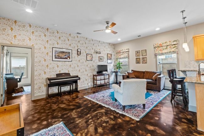 Living room featuring a wealth of natural light, concrete floors, wallpapered walls, and ceiling fan | Image 9