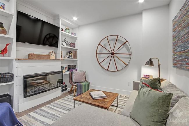 Cosy Family room with custom built in bookcases, electric fireplace, live edge mantle and a heavy duty full motion TV mount | Image 16