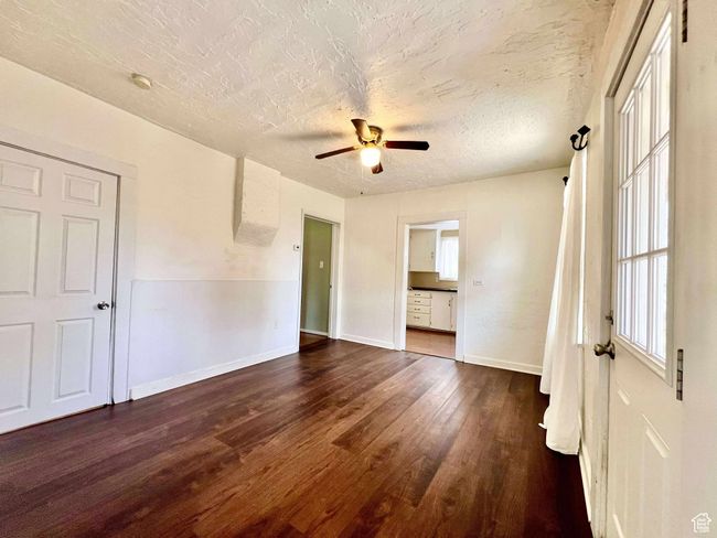 Unfurnished room with plenty of natural light, wood finished floors, a ceiling fan, baseboards, and a textured ceiling | Image 12
