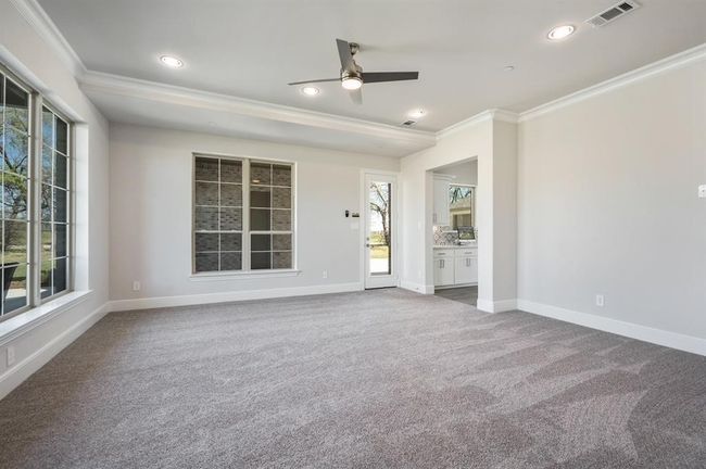 Carpeted spare room featuring crown molding, a ceiling fan, plenty of natural light, baseboards, and recessed lighting | Image 20